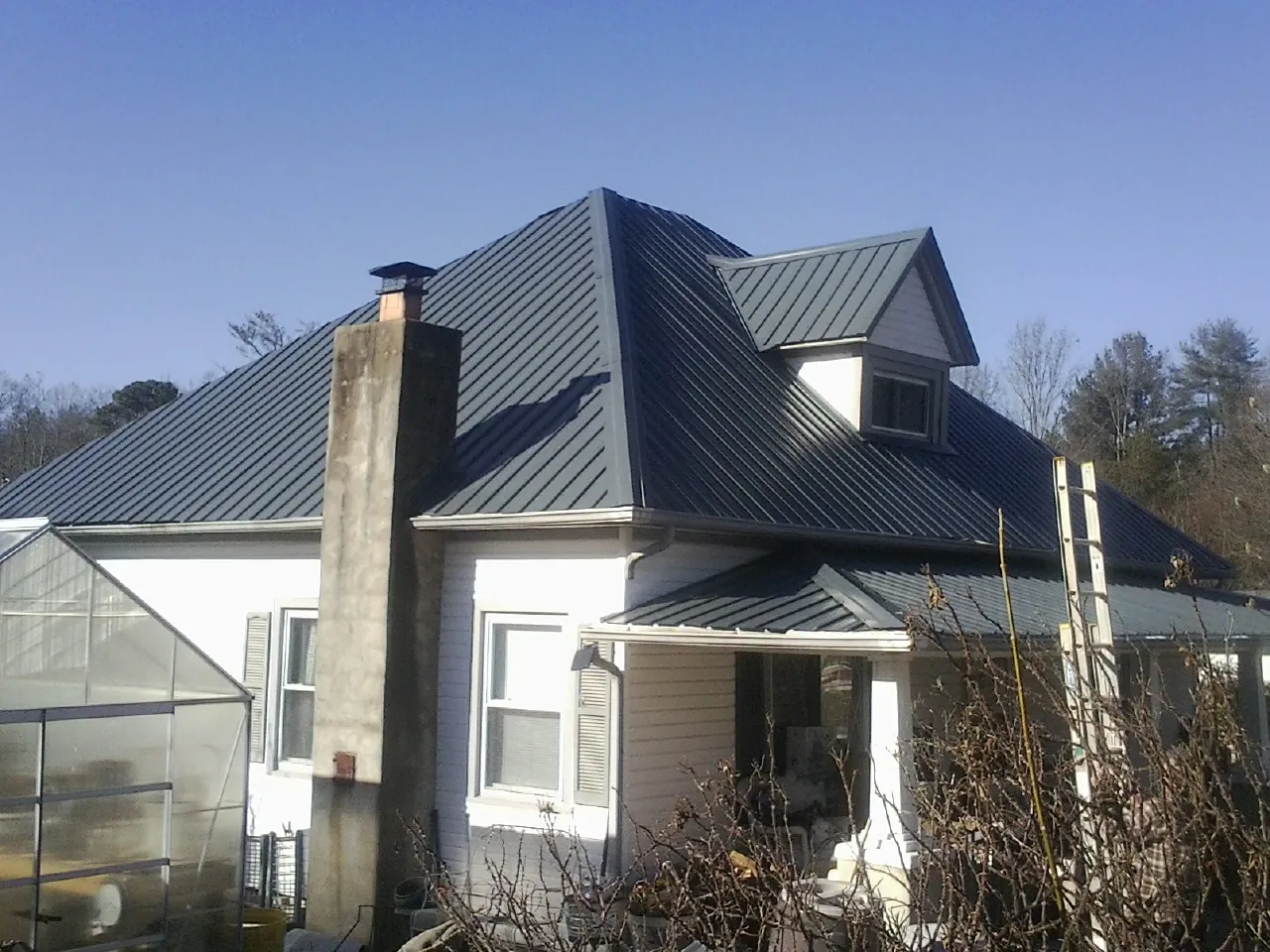 Dark blue standing seam metal roof on a white farmhouse with dormer — Slate & Tile Roof Repair by Roofing Brothers in New Carlisle