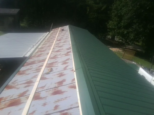 Old rusted panels beside newly installed green metal roofing — Wind Damage Roof Repair by Roofing Brothers in New Carlisle