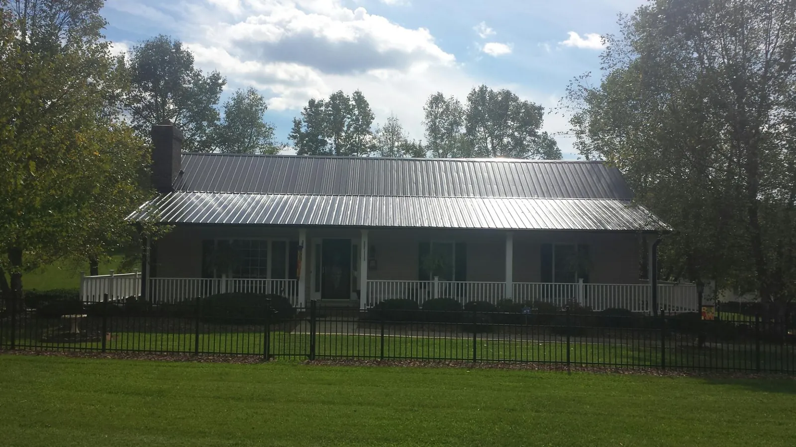 Gray metal roof on a brick ranch with a full width front porch — Gutter Guard Installation work by our crew in New Carlisle